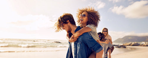 Couple enjoys a piggyback ride at the beach in summer