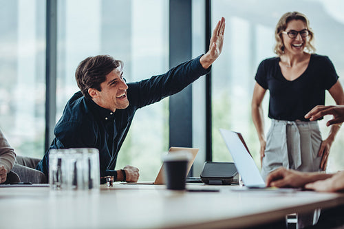 Office colleagues in meeting celebrating success