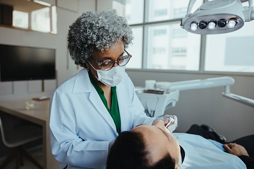 Dentist examining senior patient during clinic checkup for oral care