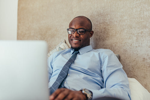 Businessman working on laptop computer sitting on bed