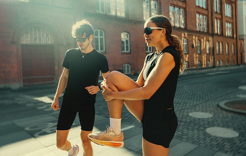 Running club warm up with young adults stretching outdoors in the city before training