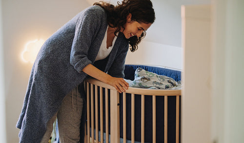 Mother putting her baby to sleep in crib