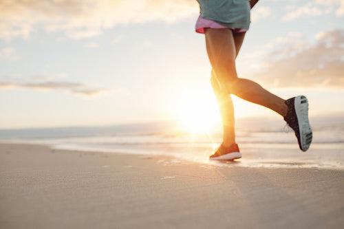 Feet of young woman jogging on the beach