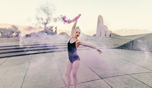 Female ballet dancer practicing dance moves using a smoke bomb