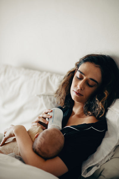 Mother feeding baby on bed