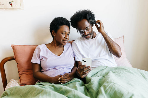 Married couple enjoying social media and technology in their bedroom