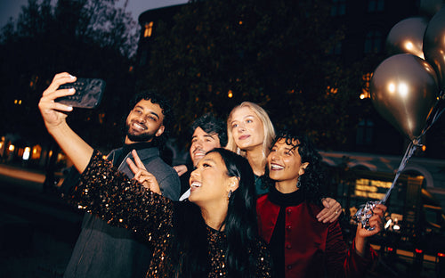 Group of friends taking selfie outdoors with balloons at a celebration