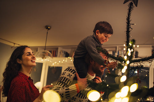 Small family decorating a Christmas tree together