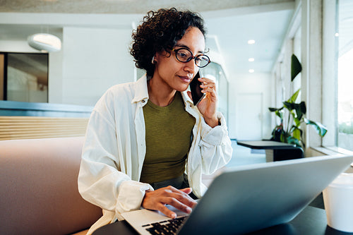 Woman on phone and laptop in lobby
