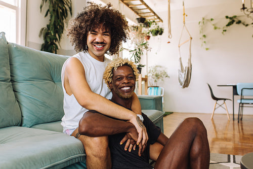 Gay couple smiling at the camera in their living room
