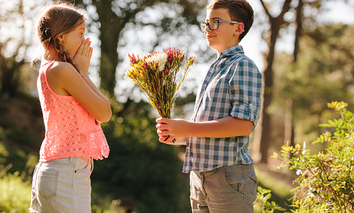 Boy proposing to his girlfriend with flowers