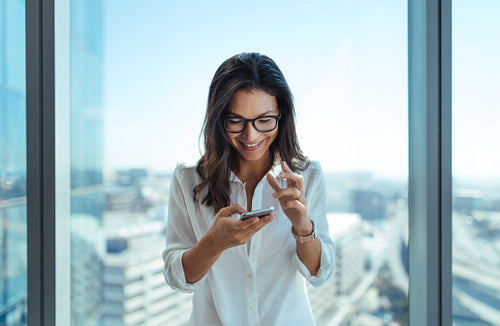 Happy businesswoman using her mobile phone at office.