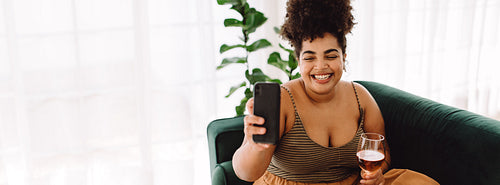 Happy woman at home taking selfie with a glass of wine