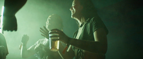 Group of lively friends dancing under the lights of a festival