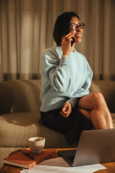 Woman talks on the phone beside a laptop in her private office workspace