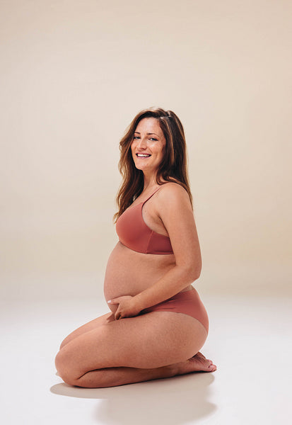 Mother-to-be embracing her baby bump, expressing body confidence in maternity lingerie