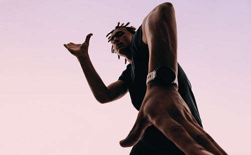 Expressive gen z dancing to music with earbuds and smartwatch in a pink silhouette studio