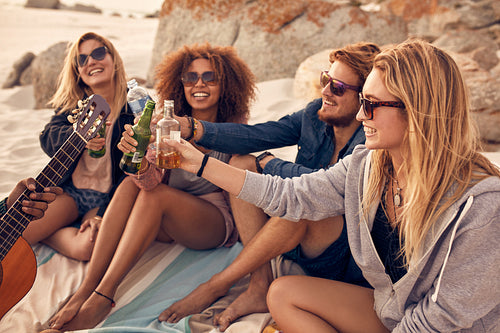Group of friends cheers with beers at the beach