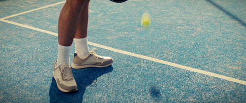 Close-up of a padel player hitting the ball on a blue court during a match