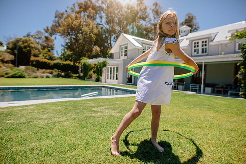 Cute little girl playing with hula hoop in the backyard