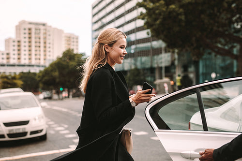 Smiling businesswoman getting into a taxi