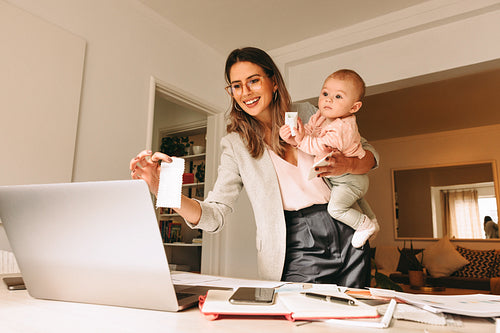 Happy working mom holding a fabric swatch during a video call
