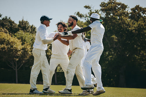 Group of cricketers celebrating a successful catch on the field