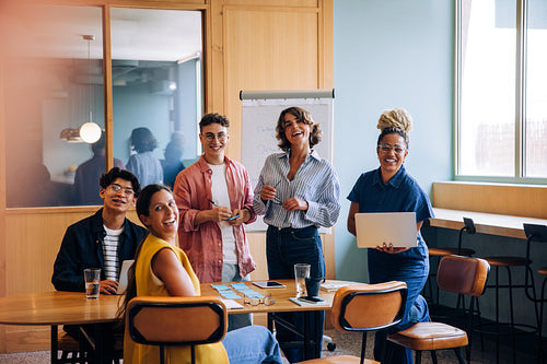 Young professionals smiling together during a casual meeting in a bright office