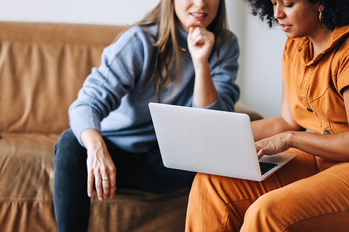 Two young businesswomen using a laptop together in an office