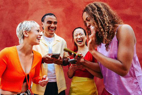 Happy friends laugh together while sharing smartphone content