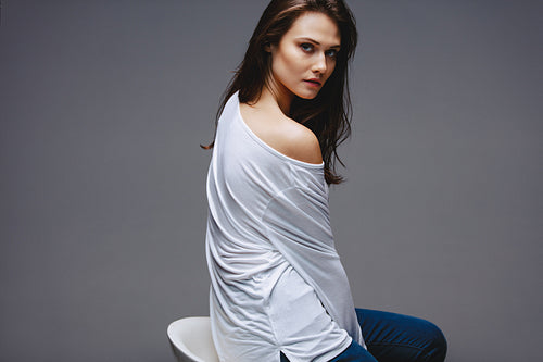 Beautiful woman in casuals sitting on stool 