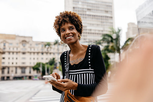 Smiling woman enjoying urban settings with her smartphone
