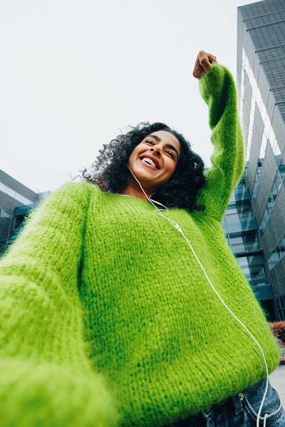 Woman joyfully dances while taking selfie outdoors in city