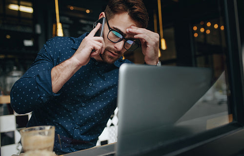 Businessman working on laptop in a cafe looking tensed