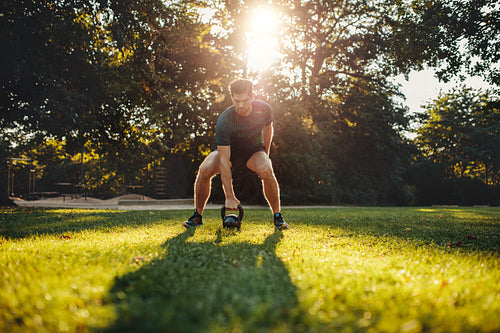 Fit young man exercising with kettlebell outdoors