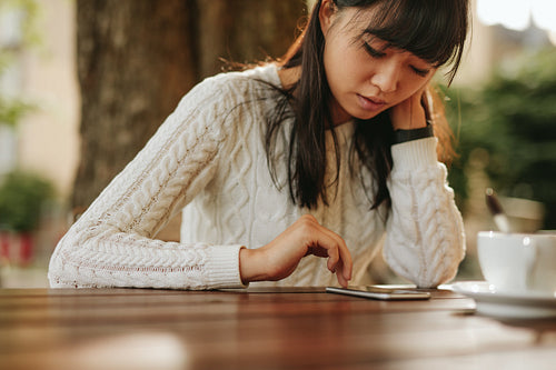 Young woman using smartphone in cafe