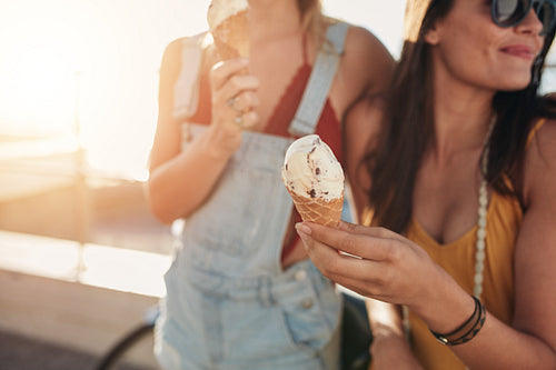 Ice cream in hand of a woman standing with her friend