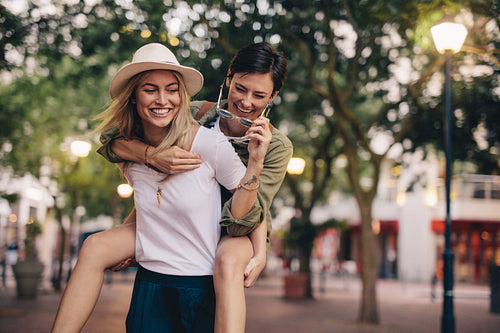 Women friends piggybacking and enjoying on city street