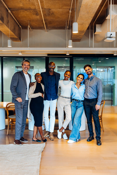Group of diverse coworkers smiling together in a stylish open office setting