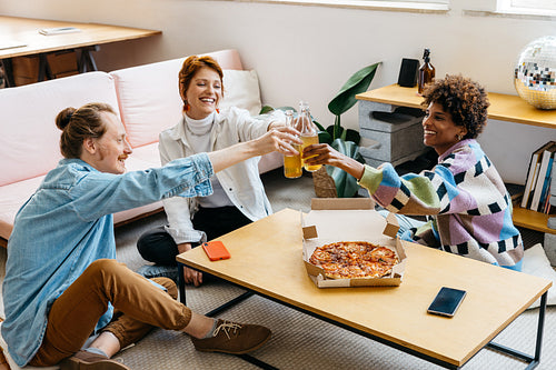 Colleagues toasting drinks over pizza in a modern co-working space