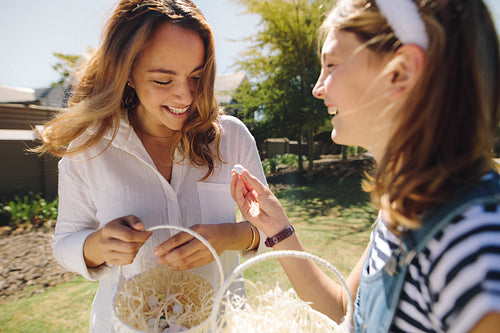 Mother and daughter walking in park carrying easter egg baskets