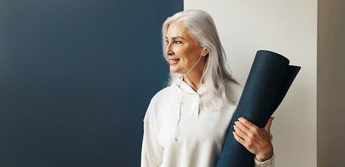 Mindful senior woman holding yoga mat in preparation for her yoga practice