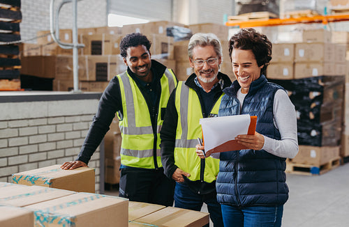 Happy warehouse manager smiling while showing her team a report