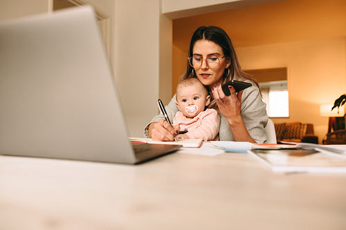 Working mom making notes during a phone call
