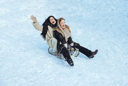 Sledding friends ride together on a snowy hill