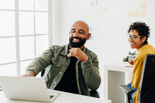 Software developer showing his colleague his work on a laptop