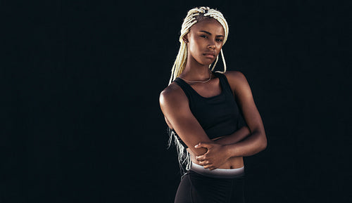Portrait of a female athlete standing against black background