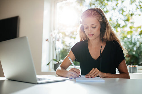 Young woman taking notes in kitchen