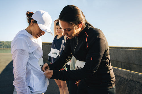 Friends preparing for a marathon by attaching race numbers