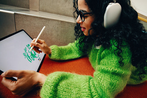 Focused young woman creating digital art on tablet in modern library